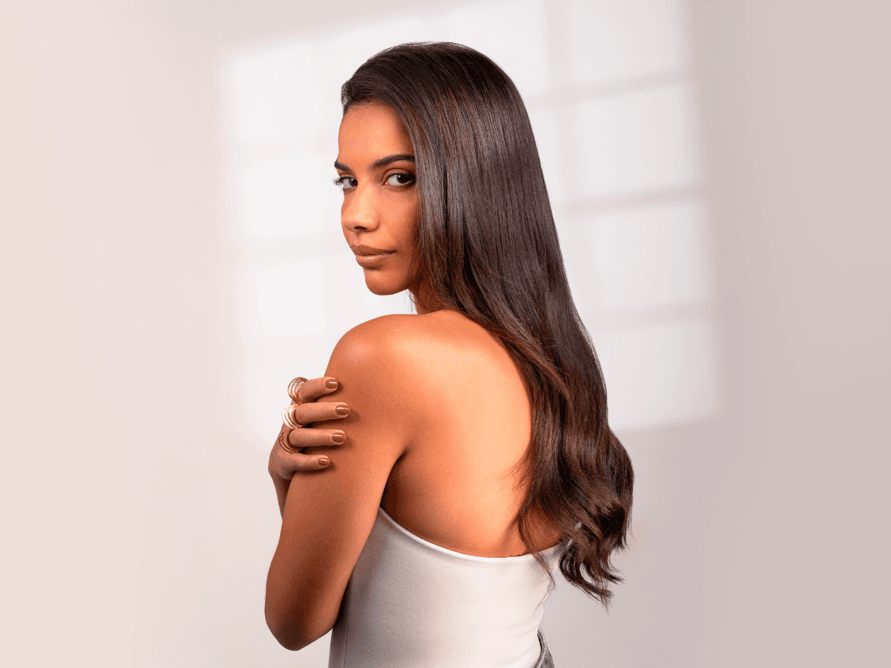 Portrait de profil d'une femme brune aux cheveux longs et ondulés, mettant en avant la brillance, la vitalité et la douceur de sa chevelure suite à un soin Botox capillaire.