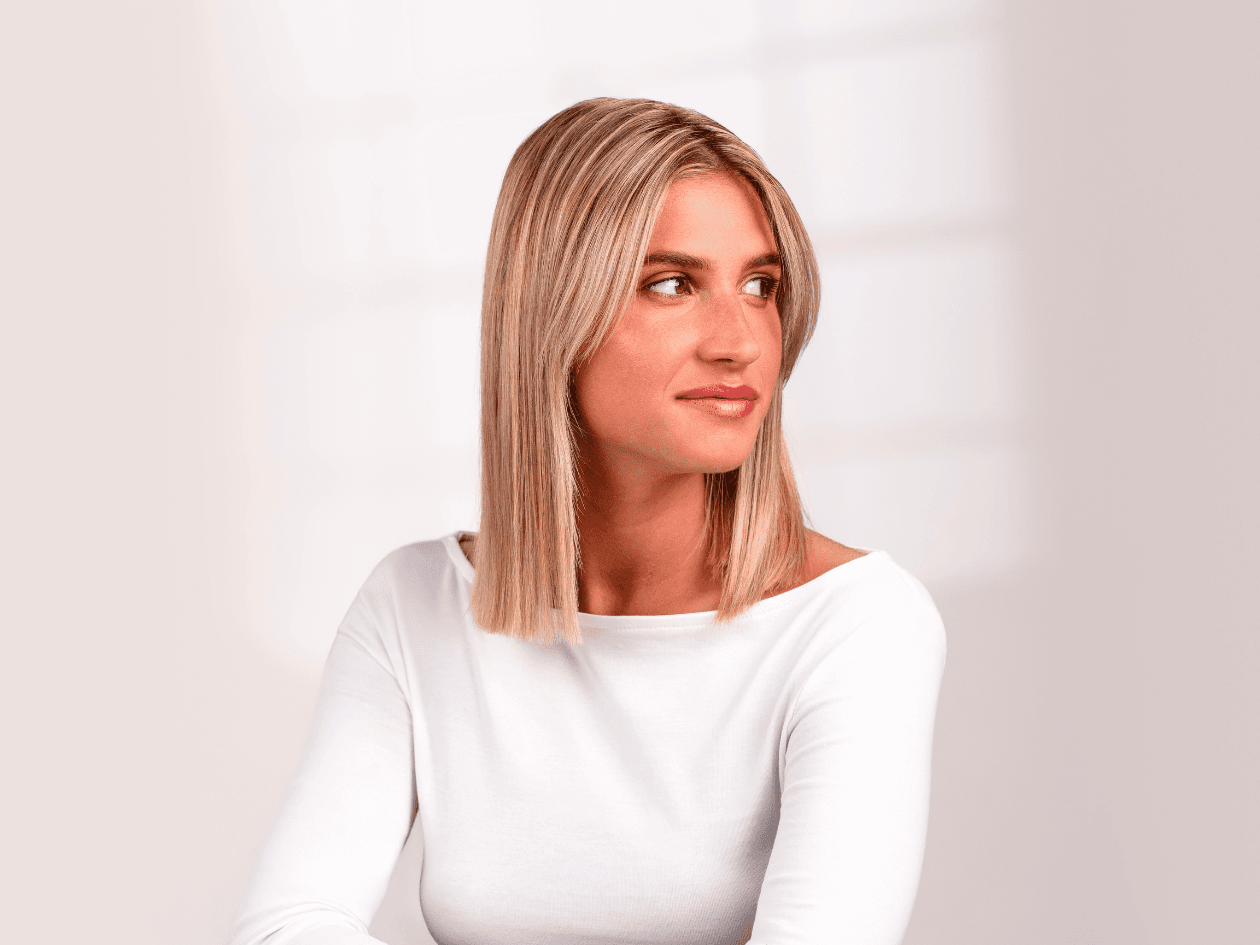 Portrait d'une femme aux cheveux blonds mi-longs, parfaitement lisses et lumineux, mettant en avant un résultat d'un soin botox capillaire.