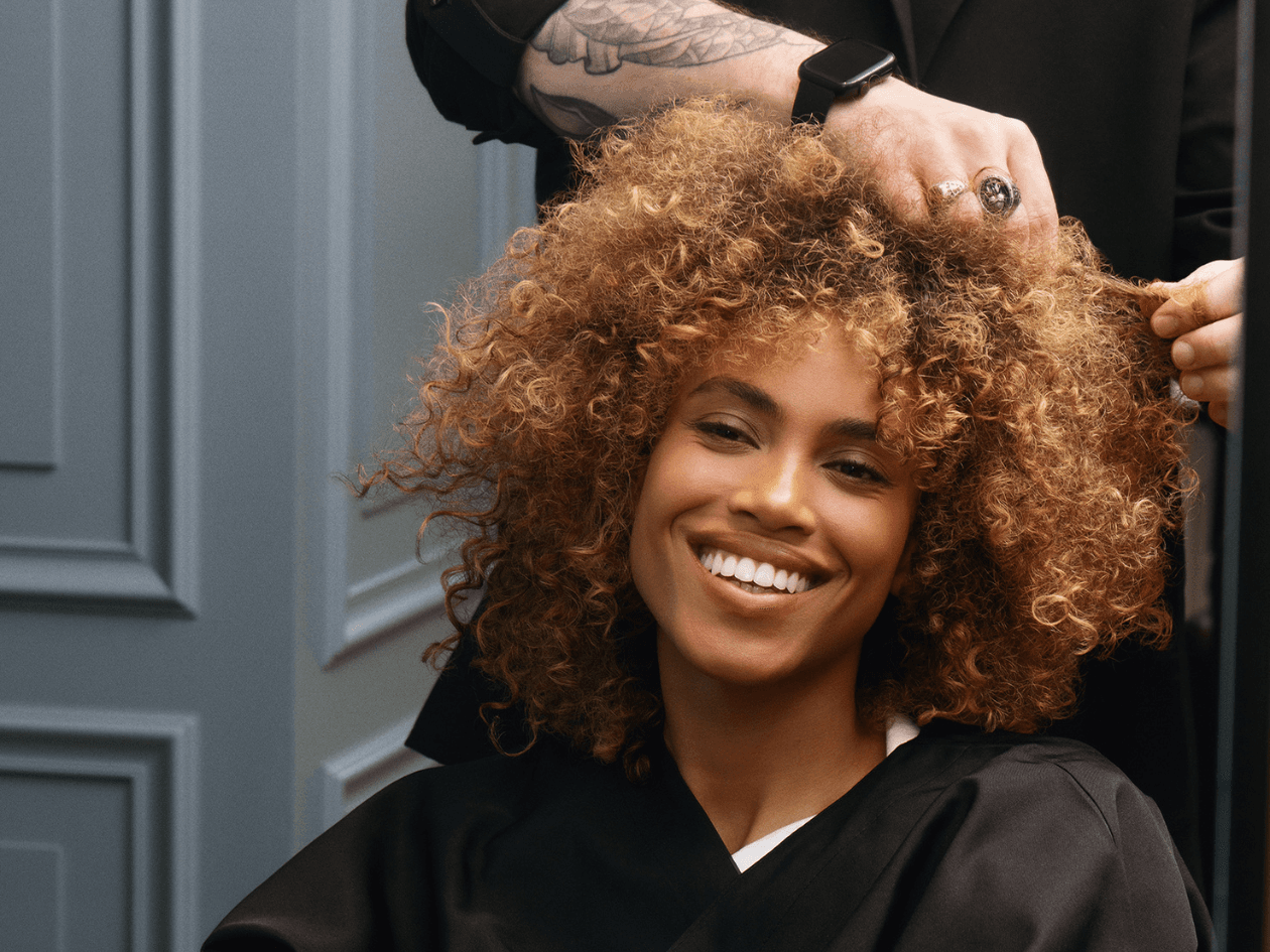 Coiffeur expert franck provost faisant un dignostic des boucles d'une cliente aux cheveux frisés miel-doré pour un résultat sur mesure.
