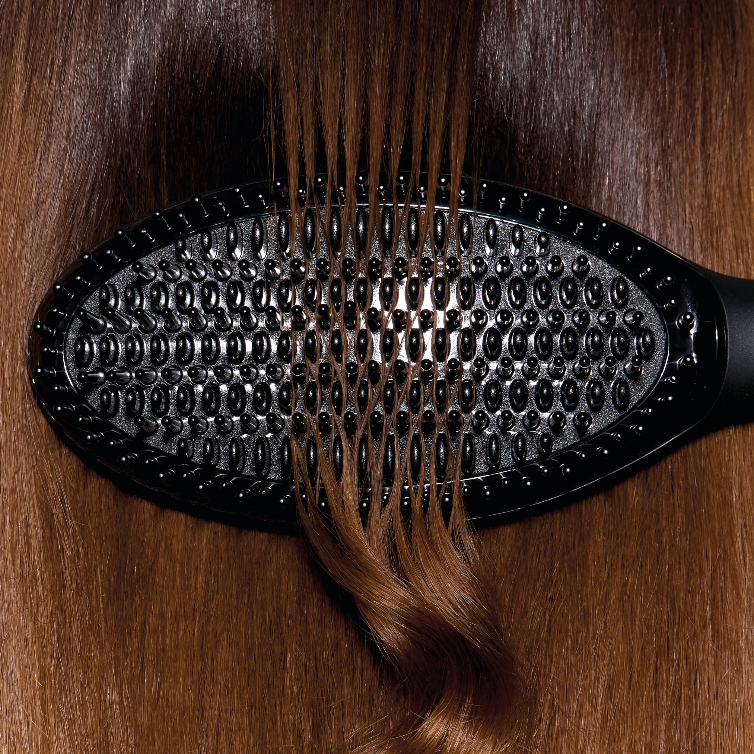 Brosse ghd glide+ en train de lisser des cheveux châtains.