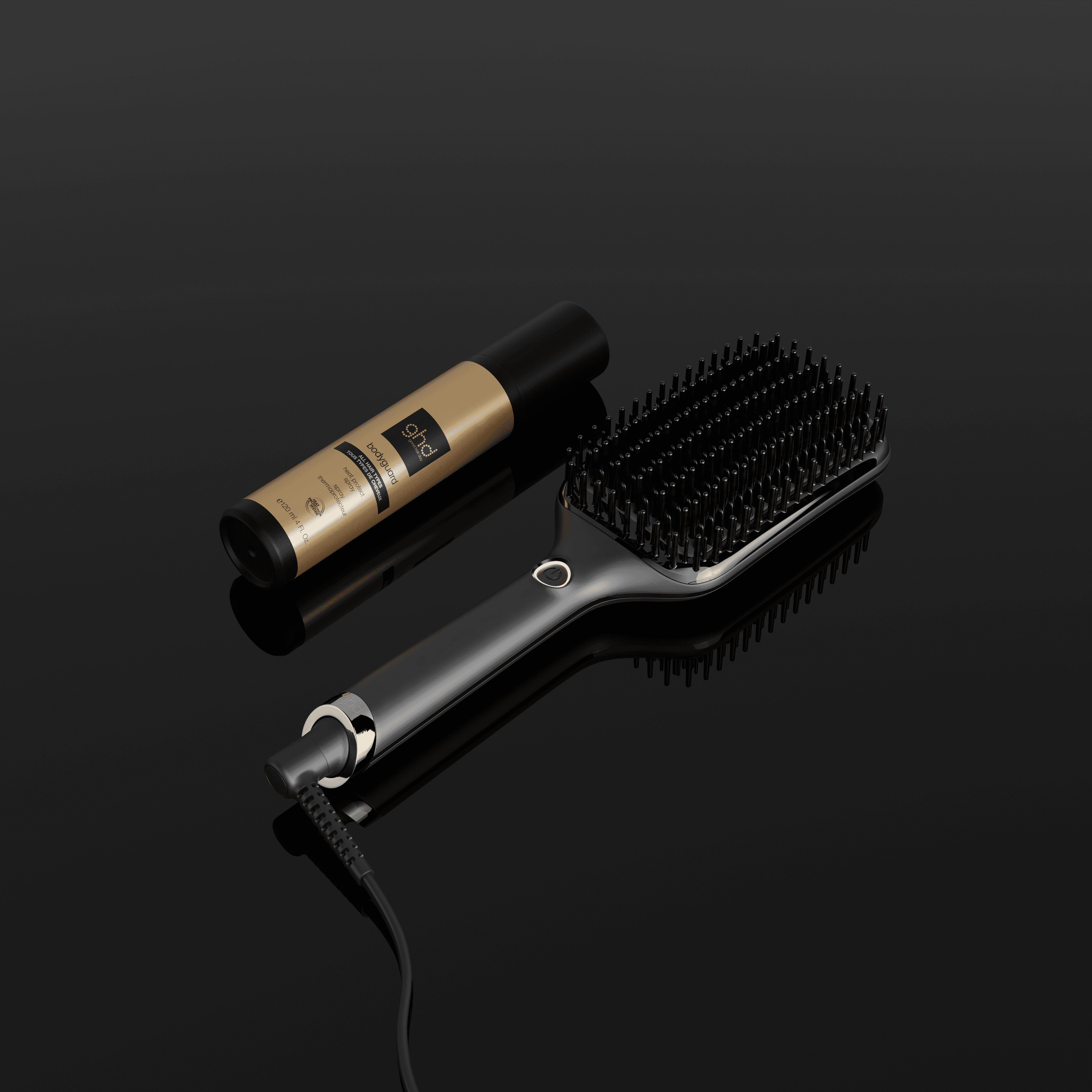 Sur un fond noir, brosse ghd glide+ max posée par terre à côté du protecteur thermique ghd.