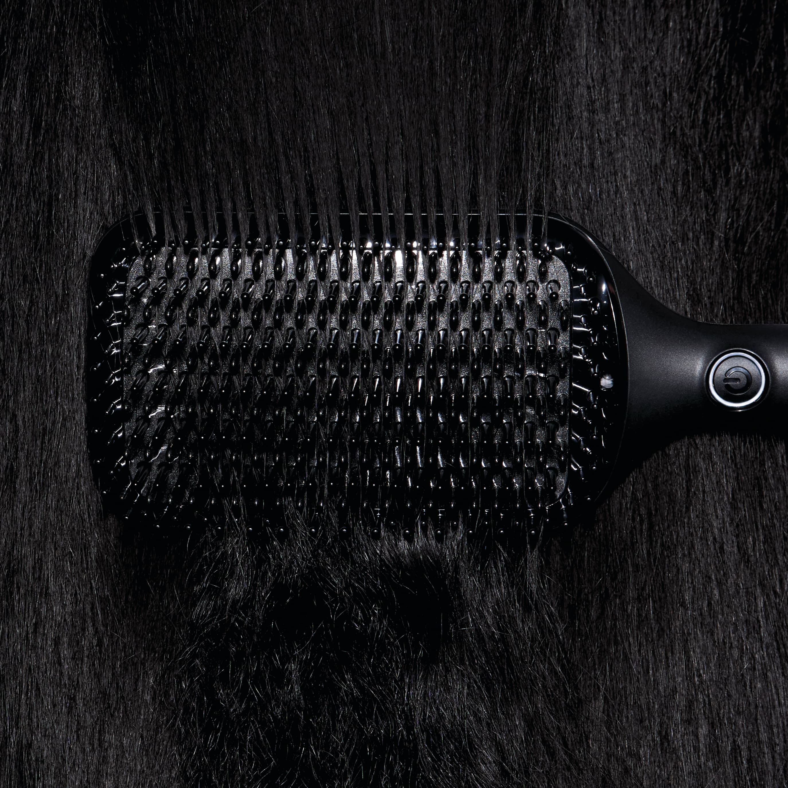 Brosse ghd glide+ max en train de lisser des cheveux bruns.
