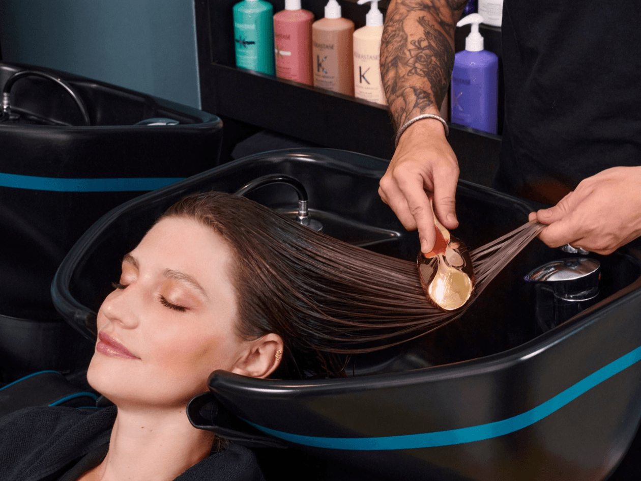 Application d’un soin Fusio-Masque Kérastase sur cheveux mouillés au bac d’un salon Franck Provost