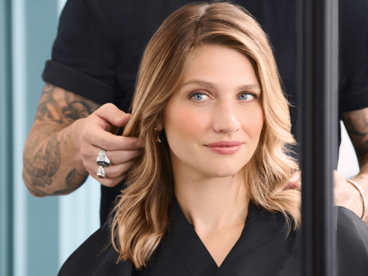 Femme aux cheveux blonds ondulés et brillants après un rituel de soin chez un coiffeur expert Franck Provost